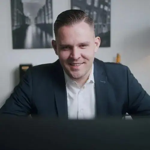 Immobilienexperte Pascal Witzens sitzend am Tisch in einer Online-Beratung für eine Kapitalanlageimmobilie
