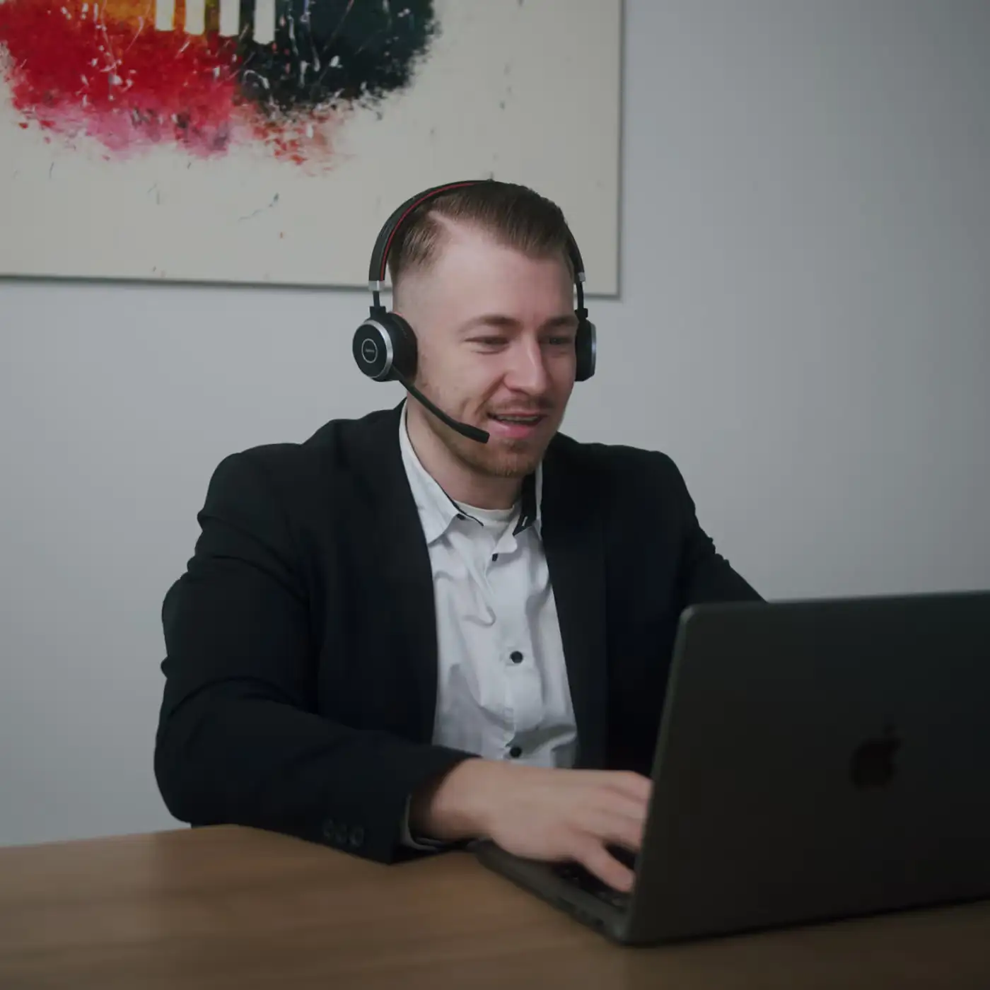 Vertriebsmitarbeiter Johann sitzend und lächelnd am Tisch in einer telefonischen Erstberatung